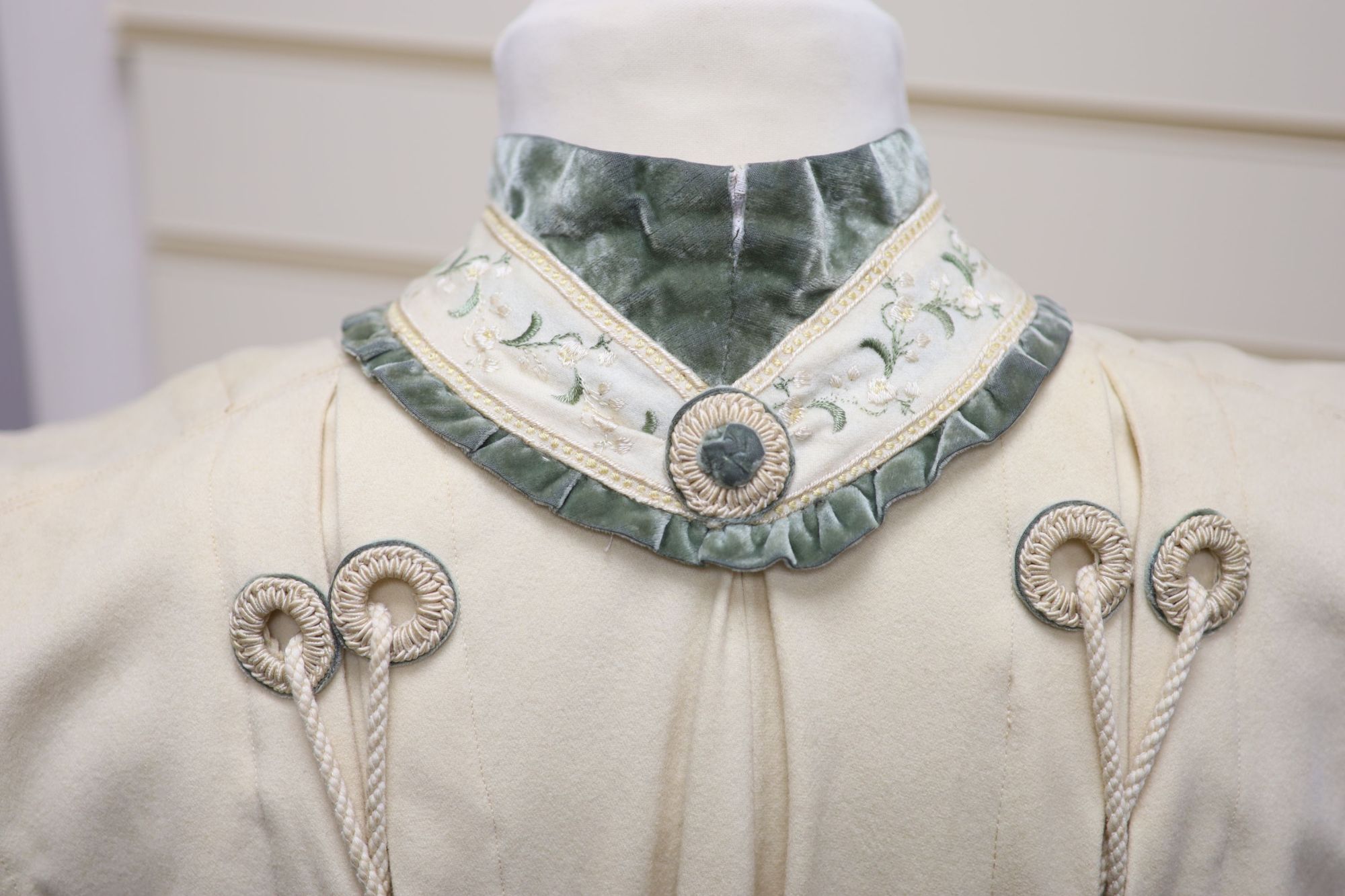 An Edwardian ladies fine cream wool coat with embroidered cuffs front edging and collar and ornate corded tasselling,